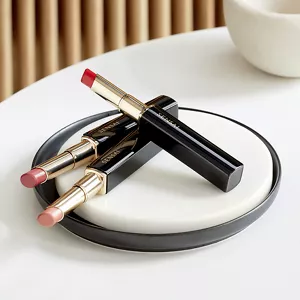 Tre ricariche di Contouring Lipstick nel supporto, una accanto all'altra, sulla superficie di marmo.